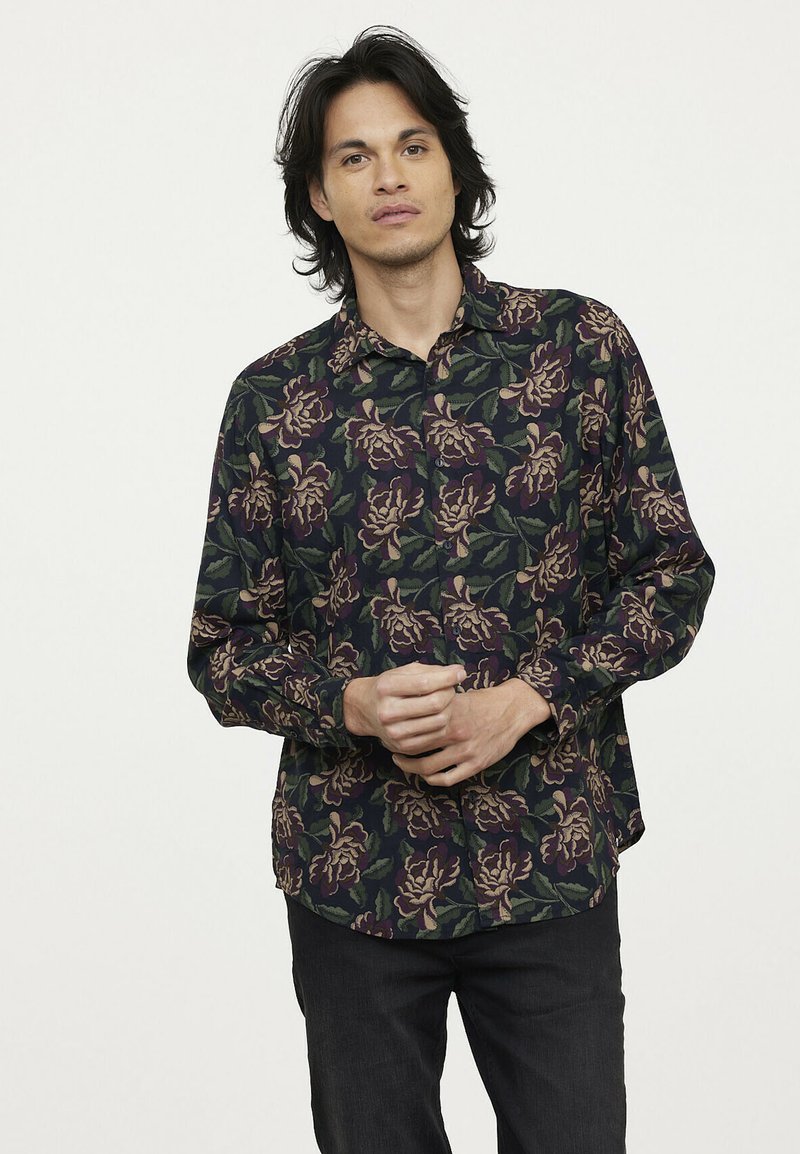 Bloemshirt met een donker marineblauwe achtergrond en grote, ingewikkelde paarse en groene bloempatronen, met knopen en lange mouwen.