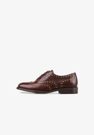 Chaussure en cuir marron à lacets avec des détails décoratifs de brogue et de petites clous dorés le long des coutures. Talon empilé bas et texture lisse.