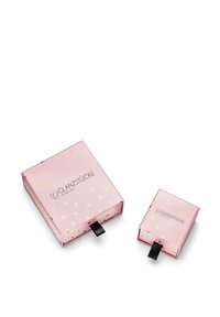 Rozā dāvanas kastes ar zelta sirdīm, viena liela un viena maza, aprīkotas ar melnu lentu un "GLANZSTÜCKE MÜNCHEN" logo.