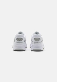 Baskets blanches Reebok avec une tige en mesh, un col rembourré et des accents gris. Détails notables : des trous de ventilation et une semelle texturée.