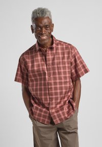 Kurzärmliges Karoshirt in Rosé- und Brauntönen, mit einem Button-Down-Kragen und einer Brusttasche. Weicher Baumwollstoff mit glatter Textur.