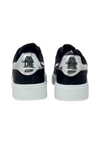 Sneaker nere con un accento lucido in argento sul tallone, una suola in gomma bianca e una parte superiore nera testurizzata. Logo "GAELLE" sulla linguetta del tallone.