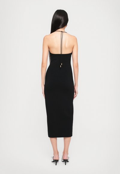 Black knit dress with a fitted silhouette, mid-calf length, low back, and adjustable spaghetti straps. Smooth texture and minimal design.