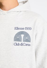Világosszürke kapucnis pulóver pamut keverékből, elöl hímzett logóval sötétkékkel, ívelt vonalakkal és a "Ellesse 1959 Club di Corsa" felirattal.