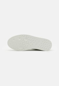 Semelle de chaussure en caoutchouc blanc avec motifs de bande de roulement circulaires et triangulaires et logo « ecco » embossé près de la section de la voûte plantaire.