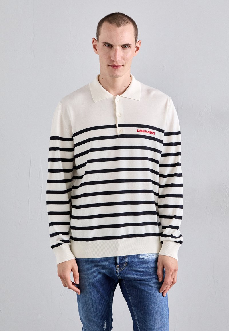 Kreem värvi pikakäiselise polo särk mustade horisontaalsete triipudega, mille rinnal on punane "DSQUARED2" logo. Kangas tundub sile ja kerge.