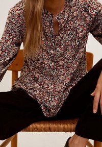 Bloemenprint lange mouwen shirt met een knooploze, ronde halslijn, gemaakt van lichte stof in donkere tinten met kleine, kleurrijke bloemen.