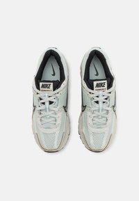 Nike Vomero 5 sneakers featuring a light mint mesh upper, black accents, padded collar, and thick white sole with subtle texture details.