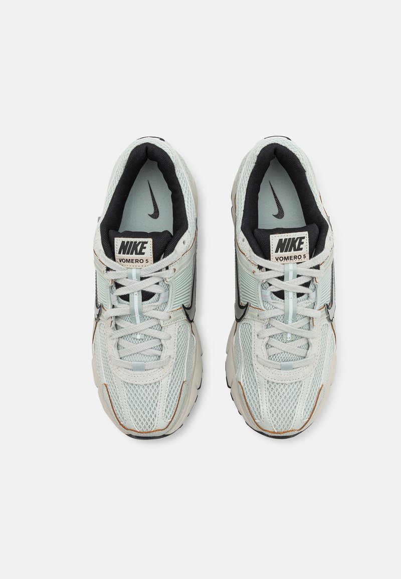 Baskets Nike Vomero 5 avec une tige en mesh vert menthe léger, des accents noirs, un col rembourré et une épaisse semelle blanche avec des détails texturés subtils.