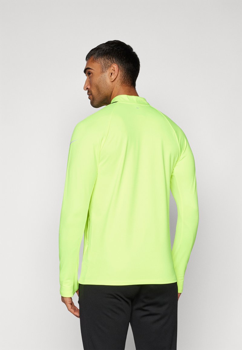 Maglietta sportiva a maniche lunghe di un brillante giallo neon, realizzata in tessuto liscio e elasticizzato. Presenta un colletto alla francese e un design slim fit.
