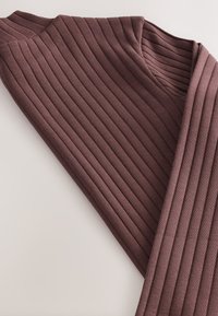 Envoltura de punto acanalado en un color malva intenso, con escote en V, textura horizontal y material suave y elástico.