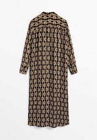 Longue robe noire avec motif de chaîne beige entrelacée, manches longues et col, vue de dos sur fond blanc.