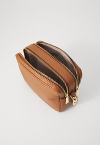 Bruine leren tas met een gestructureerd oppervlak, voorzien van dubbele ritsen en gouden hardware, met een ruime binnenkant met een bruine voering.