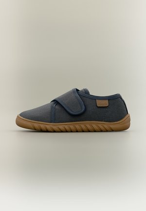 Chaussure en tissu bleu foncé avec semelle en caoutchouc marron et large bride Velcro, vue de côté sur un fond neutre.