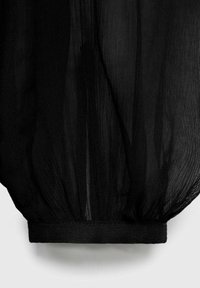 Tela negra transparente con una superficie texturizada, fruncida en el dobladillo. El material parece ligero y ligeramente translúcido.