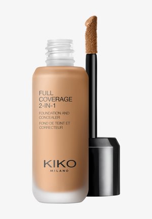Flacon de fond de teint et correcteur étiqueté "Full Coverage 2-en-1" avec une tige applicatrice trempée dans un maquillage de teinte moyen bronzé.
