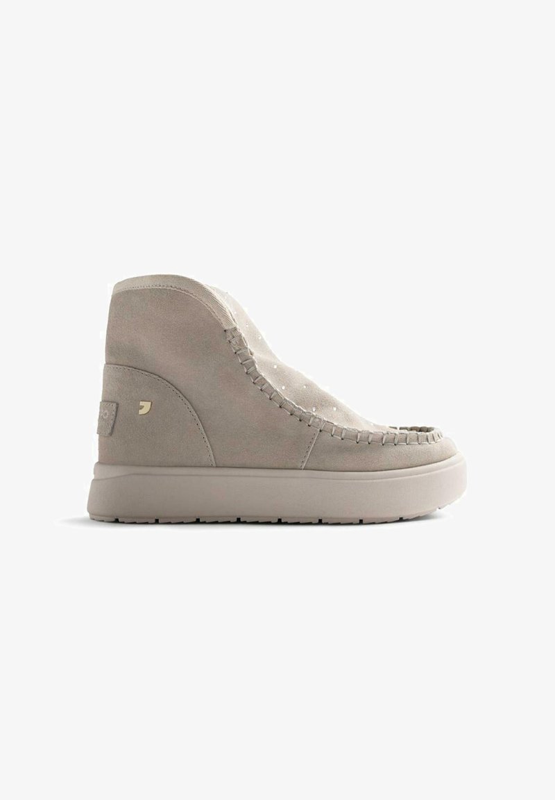 Botines de ante beige con costuras decorativas, puntera redondeada y suela plana y texturizada, con un sutil logotipo en el talón.