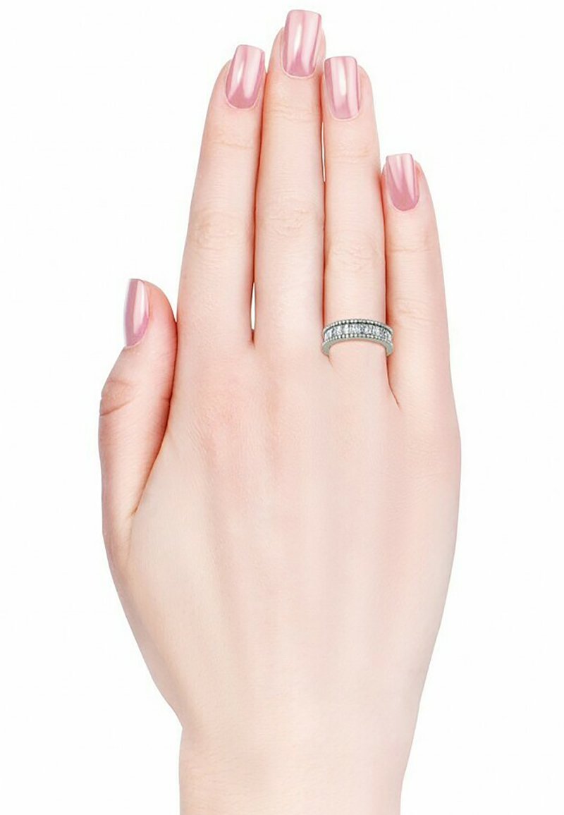 Anello d'argento con numerosi piccoli diamanti trasparenti su una mano sottile e liscia. Le unghie sono dipinte di rosa pallido, esaltando la brillantezza dell'anello.