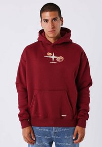 Sudadera burdeos con un bolsillo frontal tipo canguro, que presenta Gráficos florales y un logo. Textura suave, diseño casual y puños acanalados.