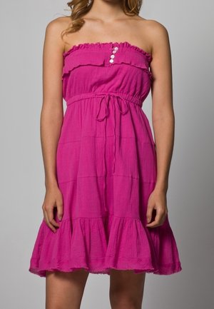 Robe sans manches rose avec un décolleté à volants, des détails de boutons, une taille à cordon et un ourlet évasé. Confectionnée en tissu texturé.