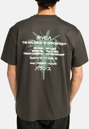 Donkergrijze t-shirt met groene palmgrafiek en witte tekst, inclusief merknaam "RVCA" en verschillende zinnen. Gemaakt van katoen, met een ontspannen pasvorm.