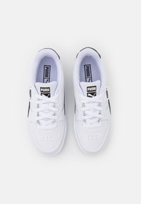Baskets blanches de sport avec un matériau lisse ressemblant à du cuir, des accents noirs et un design classique à lacets. Présente des perforations et un détail de logo.