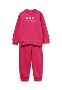Conjunto de sudadera fucsia y pantalones a juego. La sudadera presenta tres corazones blancos y el texto "united colors of Benetton". Textura suave.