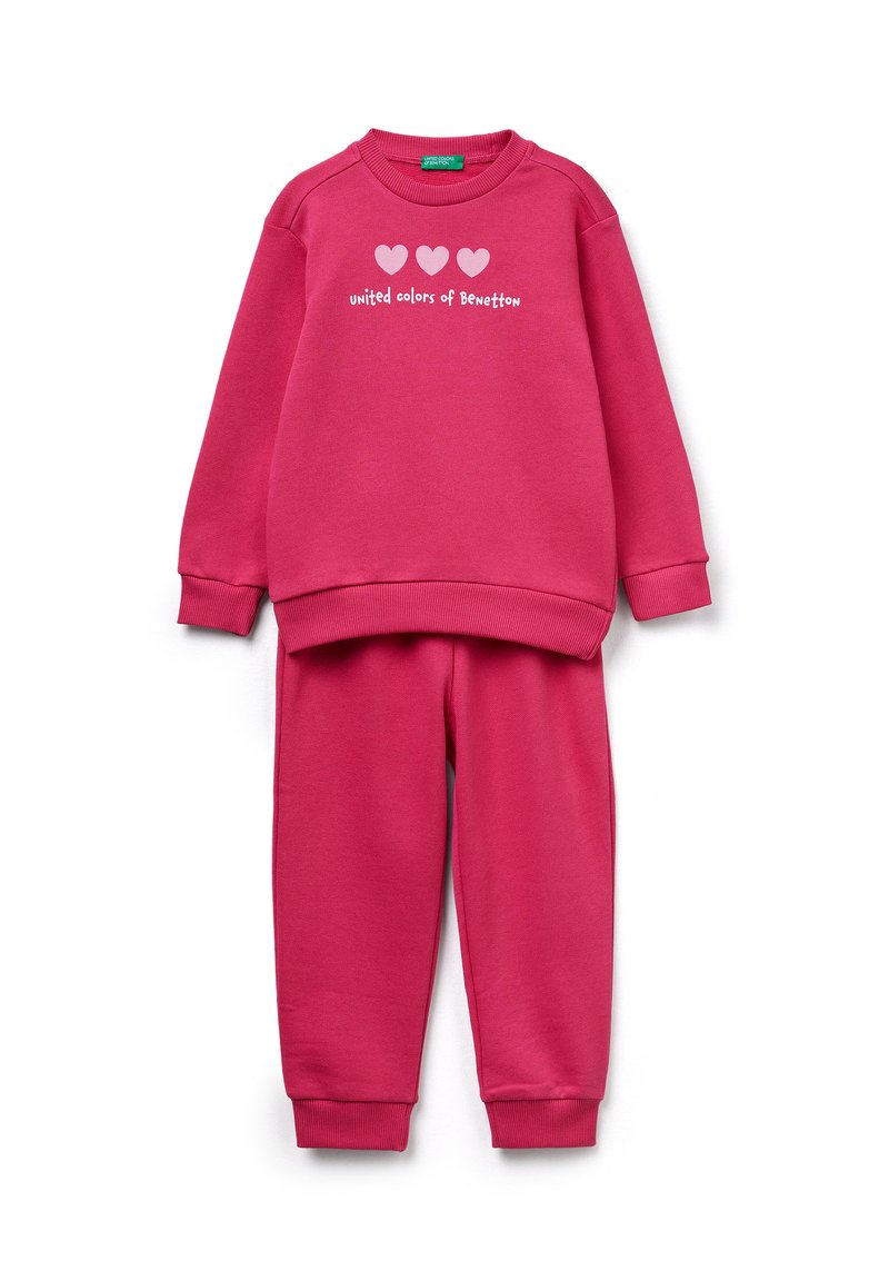 Conjunto de sudadera fucsia y pantalones a juego. La sudadera presenta tres corazones blancos y el texto "united colors of Benetton". Textura suave.