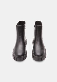 Botine din piele neagră, până la gleznă, cu o textură netedă, vârf rotund și talpă groasă din cauciuc. Include fermoare laterale pentru o îmbrăcare ușoară.