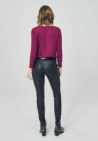 Burgundy lättviktig topp med långa ärmar, i kombination med åtsittande svarta läderbyxor och klackade ankelstövlar med silvernitar.