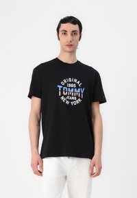 Sort bomulds t-shirt med rund hals, kortærmer og et farverigt grafisk design med teksten "TOMMY JEANS NEW YORK".
