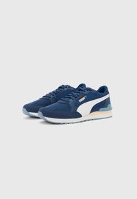 Blue athletic sneakers with a textured fabric upper, white accents, flat laces, and a rubber sole featuring a light blue outsole.