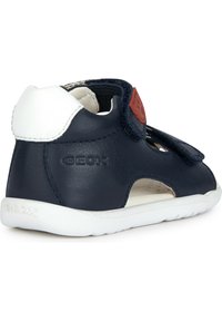 Sandalo per bambini in pelle blu navy con suola in gomma bianca, cinturino regolabile in Velcro e design con aperture per la traspirabilità.