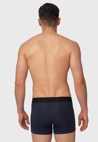 Mørkeblå bomulls boxershorts med svart elastisk midjebånd med preget tekst. Glatt tekstur, tettsittende design og midt-lår lengde.