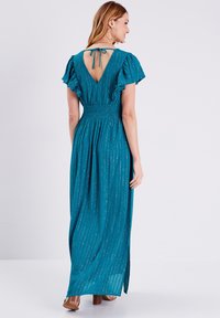 Robe maxi teal avec des manches volantées, taille froncée et dos en V. Présente des rayures verticales et une fente latérale, fabriquée à partir d'un tissu léger.
