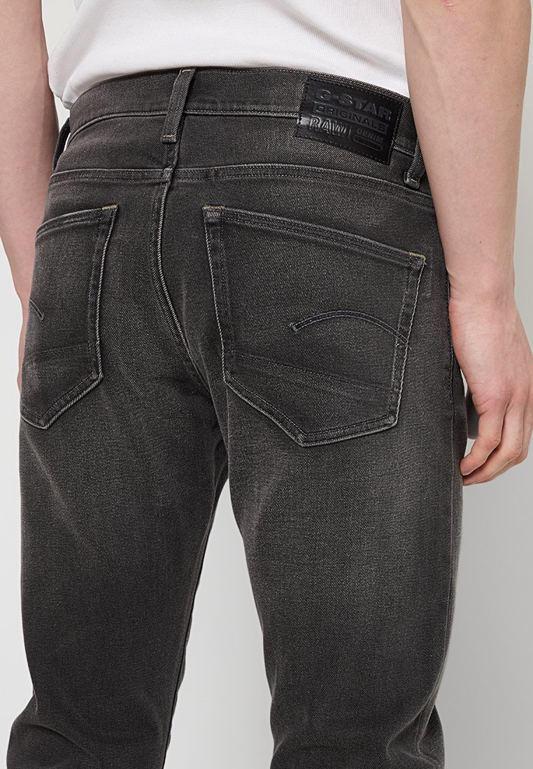 Donkergrijze spijkerbroek met een reguliere pasvorm, voorzien van twee achterzakken, zichtbare stiksels en een leren merklabel op de tailleband.