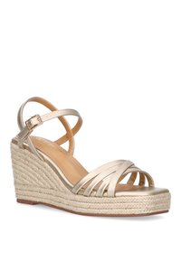 Sandalias doradas de cuña con suela de yute trenzado, que cuentan con múltiples tiras y una correa ajustable en el tobillo. Textura suave, diseño de punta abierta.