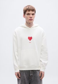 Λευκό φούτερ με κουκούλα από απαλό ύφασμα, με σχέδιο κόκκινης οριγκάμι καρδιάς και το κείμενο «HUGO» από κάτω, με τσέπη καγκουρό και ριμπ μανσέτες.