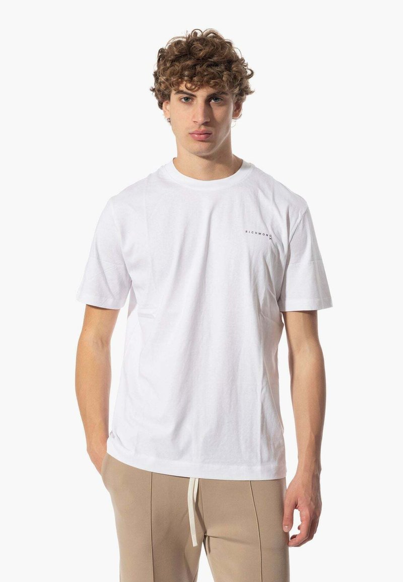 T-shirt bianco in cotone con maniche corte, colletto rotondo e un piccolo logo grigio sul lato sinistro del petto. Presenta una vestibilità comoda e una trama morbida.
