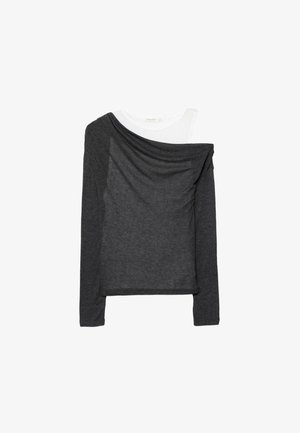 Haut à manches longues gris foncé superposé sur un t-shirt blanc à col rond, présenté à plat sur un fond blanc.