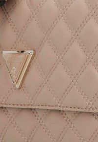 Quilted rosa synthetische Handtasche mit einem goldenen metallischen Dreiecks-Logo. Eine Nahtdetails verleihen Textur und Dimension.