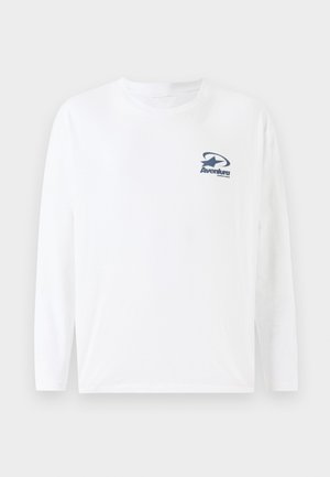 Bijela majica dugih rukava od pamuka, s mornarskoplavim logom na prsima. Okrugli izrez i ravni rub s dugim, udobnim rukavima.