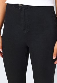 Svarta denim högmidjade skinny jeans med framknäppning, med en mjuk textur och subtila sömdetaljer.