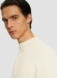 Crème kleurige zip-neck pullover van zachte gebreide stof, met een hoge halslijn, een geribbelde kraag en een gladde textuur. Te verstellen met een rits.
