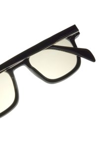 Černé sluneční brýle s robustními, obdélníkovými rámy, které mají světlé čočky. Stranice jsou štíhlé s lesklým povrchem. Žádné viditelné logo.