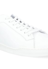 Białe skórzane sneakersy o gładkiej fakturze, zaokrąglonym nosku, sześciu oczkach na sznurówki oraz białej gumowej podeszwie z teksturowanym wzorem antypoślizgowym.