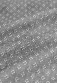 Grauer Stoff mit einem dezenten weißen Blumenmuster. Die Textur ist glatt mit einer leicht gewebten Qualität. Das Design ist gleichmäßig über die gesamte Fläche verteilt.