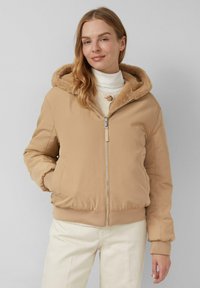 Beige bomberjack met een gevoerde capuchon van bont, ritsluiting, ribgebreide manchetten en zoom. Draag het over een licht sweater, in combinatie met crèmekleurige broek.