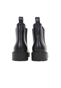 Svarta läderankelstövlar med elastiska sidopaneler, robusta gummisulor och dragflikar bak för enkel påtagning. Slät yta, minimalistisk design.