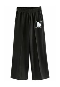 Pantaloni svasati neri in tessuto morbido con vita elastica, dotati di tasche laterali e di un logo circolare bianco con testo sul lato sinistro.